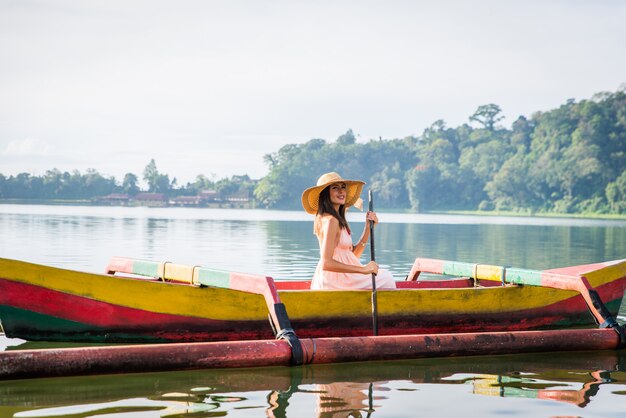 Young woman traveler paddling on a wooden boat at Pura Ulun Danu Bratan