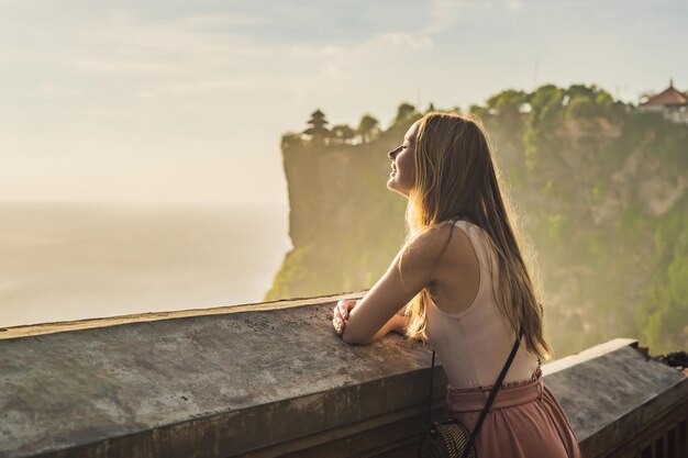 Pura Luhur Uluwatu 사원 발리 인도네시아에서 젊은 여성 여행자 푸른 하늘과 바다와 놀라운 풍경 절벽