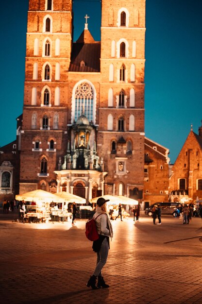 Young woman traveler in st mary's basilica in main square of krakow wawel castle historic center city with ancient architecture