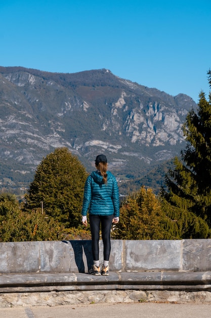 山とカメラに背を向けて立っている若い女性旅行者