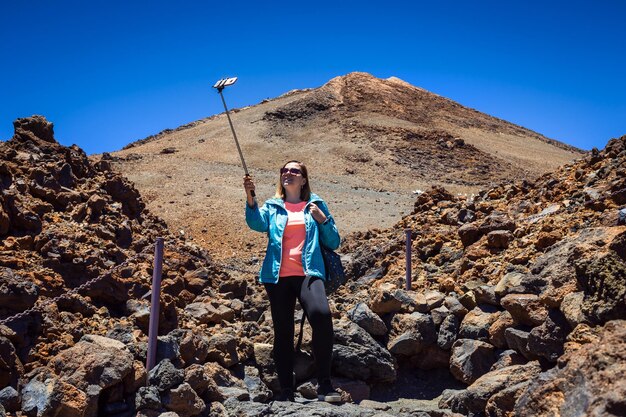 サングラスをかけた若い女性旅行者は、スペインのテネリフェ島カナリア諸島のテイデ火山を見下ろして自分撮りをします