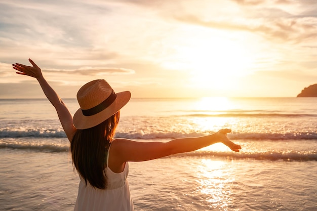 静かなビーチで美しい夕日を歩いて楽しんでいる若い女性旅行者夏休みのコンセプトで旅行