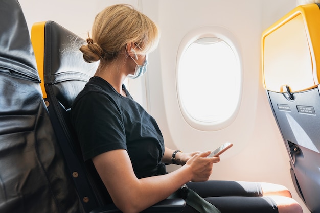 Young woman traveler wearing prevention mask during a flight inside an airplane