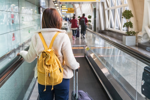 荷物と空港でのバックパックを持つ若い女性旅行者