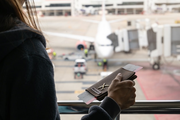 飛行機を見てパスポートを持っている荷物と若い女性旅行者