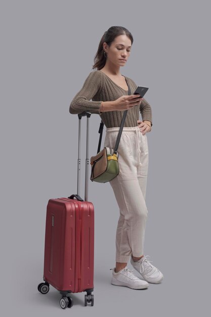 Young woman traveling alone and connecting with a smartphone she is booking services online