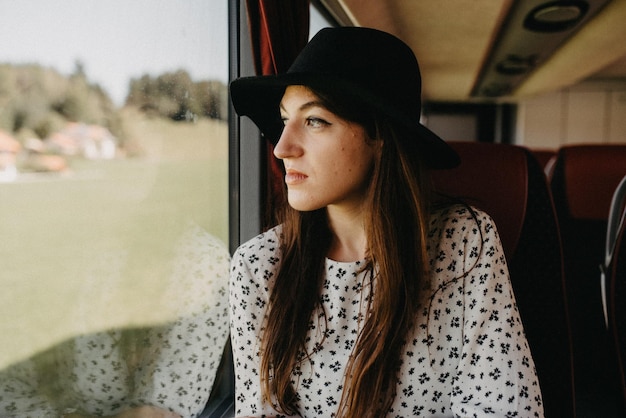 Young woman traveling on a bus looking out of the window in thought