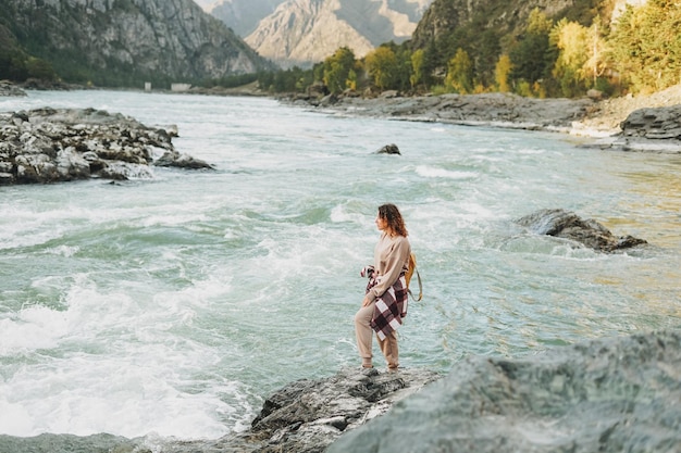 Young woman traveller in casual with backpack on mountain river on the sunset