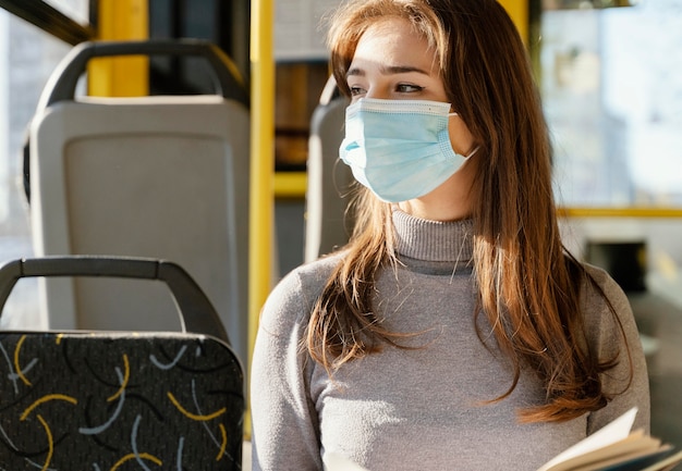 Giovane donna che viaggia in autobus urbano leggendo un libro