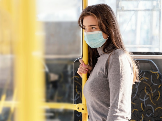 Photo young woman travelling by city bus with surgical mask