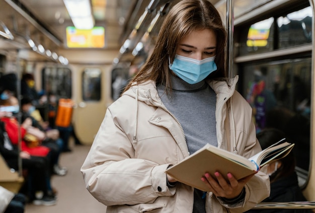 Foto giovane donna che viaggia in metropolitana leggendo un libro