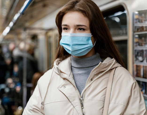 Giovane donna che viaggia in metropolitana che indossa una mascherina chirurgica
