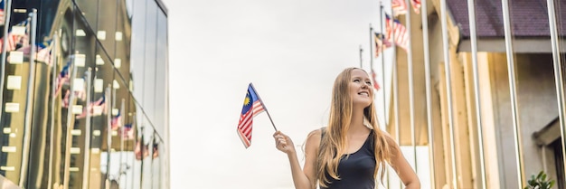 Young woman travels in malaysia holds the malaysian flag banner long format