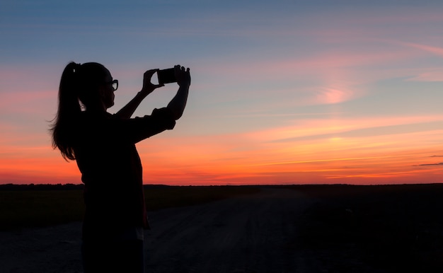 Молодая женщина путешествует и фотографирует закат. Природа