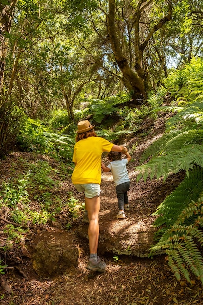 Una giovane donna che fa trekking su un sentiero a la llania, sulle isole canarie di el hierro, lussureggiante paesaggio verde insieme a suo figlio