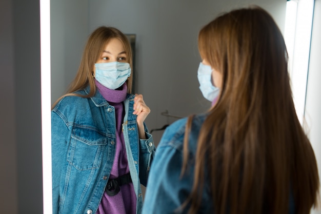 若い女性が店の鏡付きの楽屋で服を試着