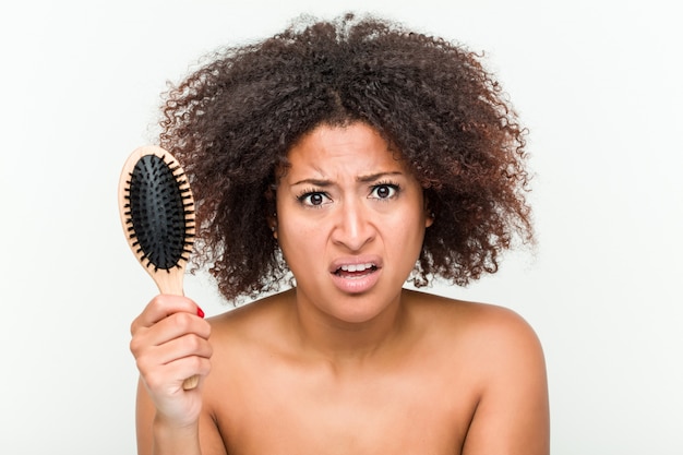 Young woman trying to brush her curly hair