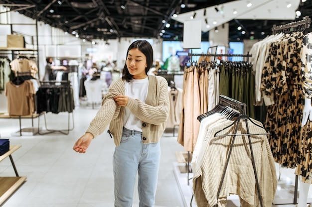 Young woman trying on cardigan in clothing store