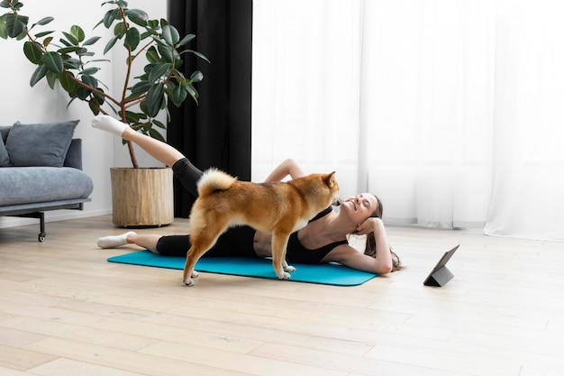 Photo young woman trying to exercise next to her dog