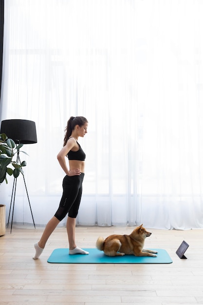 Foto giovane donna che cerca di fare sport a casa con il suo cane