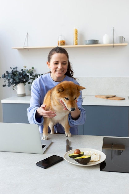 Young woman trying to work while her dog is distracting her