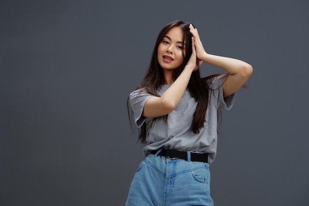 Young woman in a tshirt and jeans posing Youth style Gray background