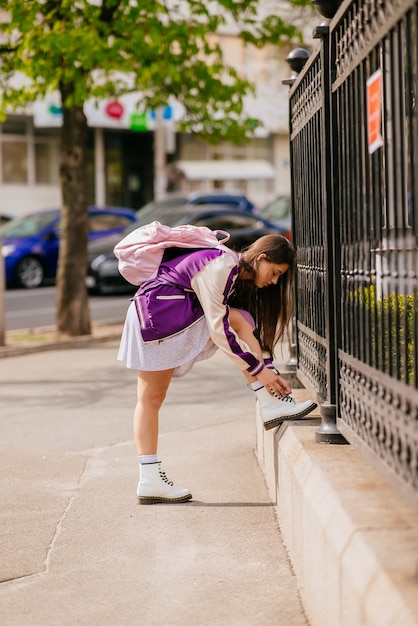 彼女の白いブーツに靴ひもを結ぶ若い女性