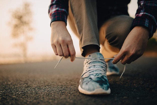 Young woman tying her shoelaces at sunset