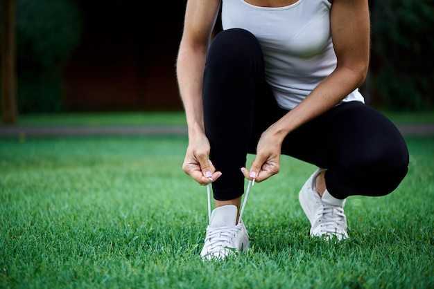 Young woman tying shoelaces before running