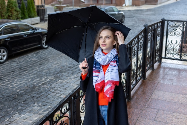 Young woman under an umbrella on a city street