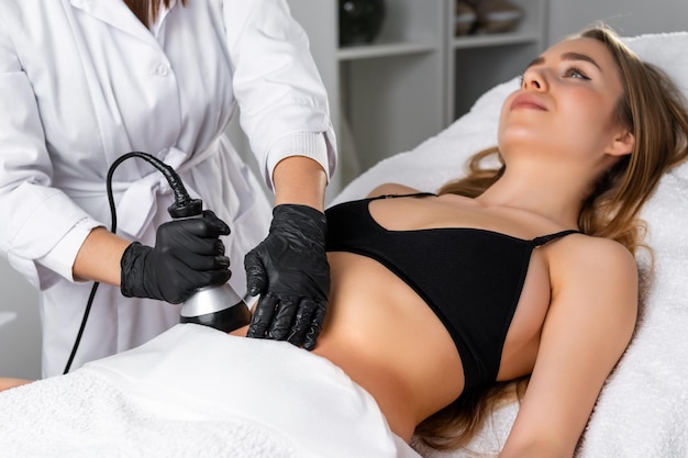 Young woman undergoes an ultrasound cavitation procedure for skin tightening