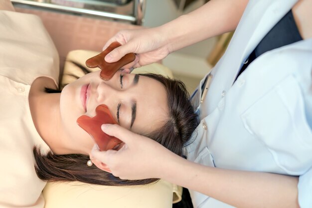 young woman undergoing acupuncture treatment by jade at the health spa