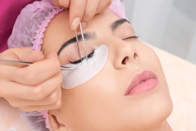 Young woman undergoing eyelash extensions procedure closeup