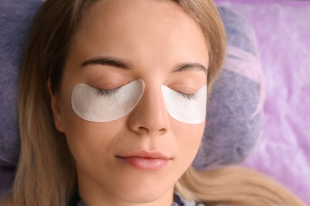 Young woman undergoing eyelash extensions procedure, closeup