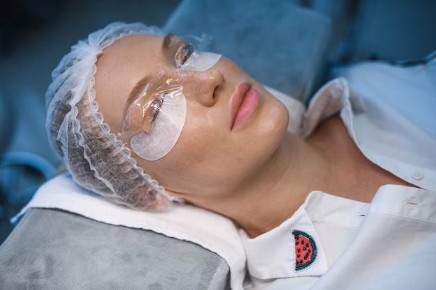 Photo young woman undergoing procedure of eyelashes lamination in beauty salon, closeup