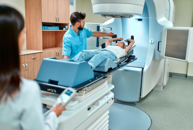 Young woman undergoing radiation therapy for cancer under the\
supervision of doctors