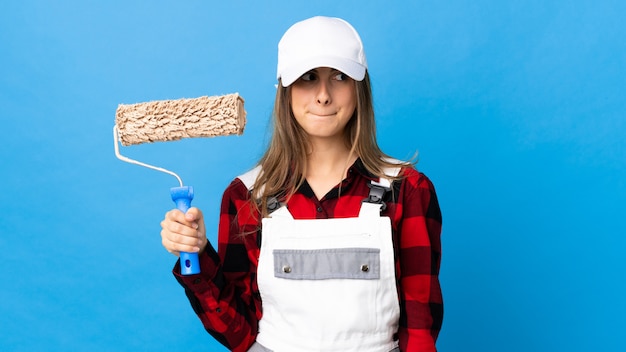 Giovane donna in uniforme con rullo di pittura