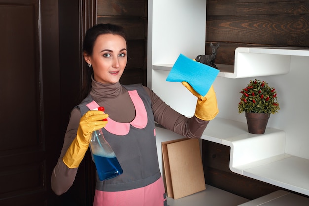 洗浄スポンジと洗浄剤で制服を着た若い女性。ハウスキーピングのコンセプト