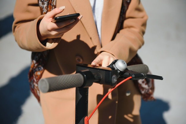 若い女性が携帯電話で電動スクーターのロックを解除します