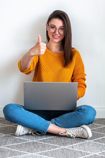 Young woman use laptop sitting on carpet on white background