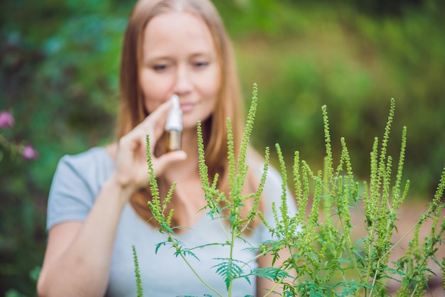 Young woman uses a spray from an allergy because of an allergy to ragweed