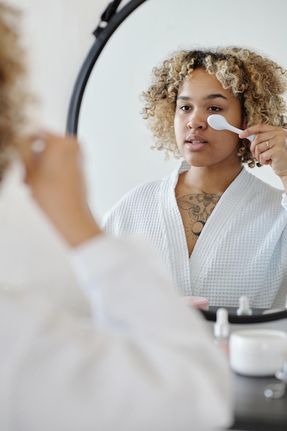 Foto giovane donna che utilizza lo strumento di trattamento di bellezza mentre si prende cura del viso