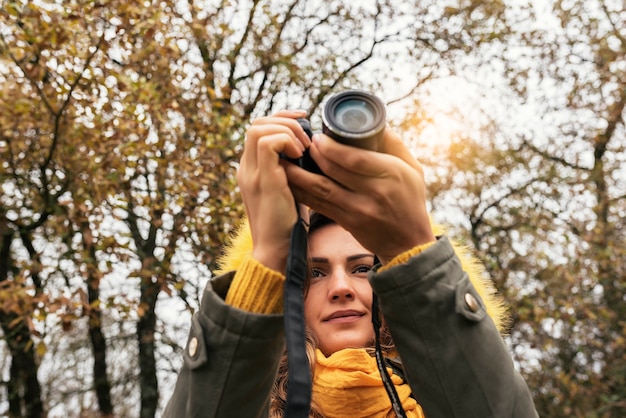 Young woman using a camera to take photo at the forest.