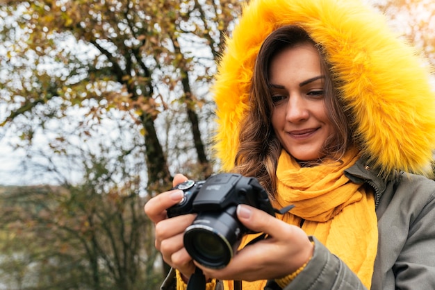 Young woman using a camera to take photo at the forest.