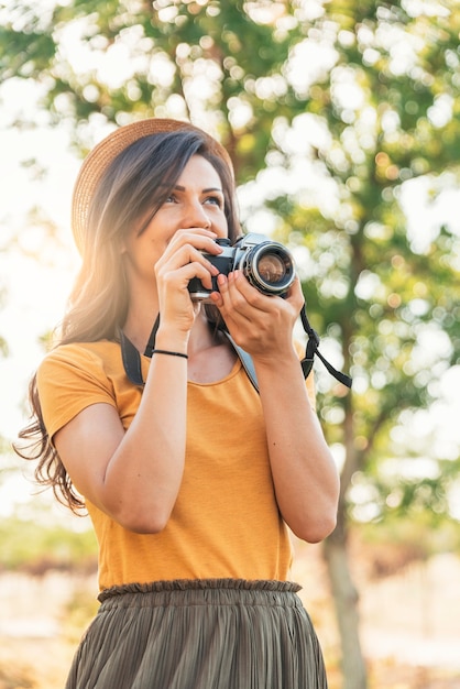 公園で写真を撮るためにカメラを使用して若い女性。