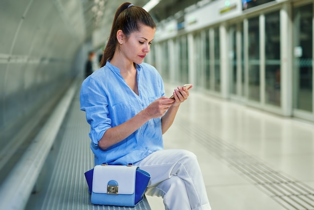 Young woman using cell phone in subway station