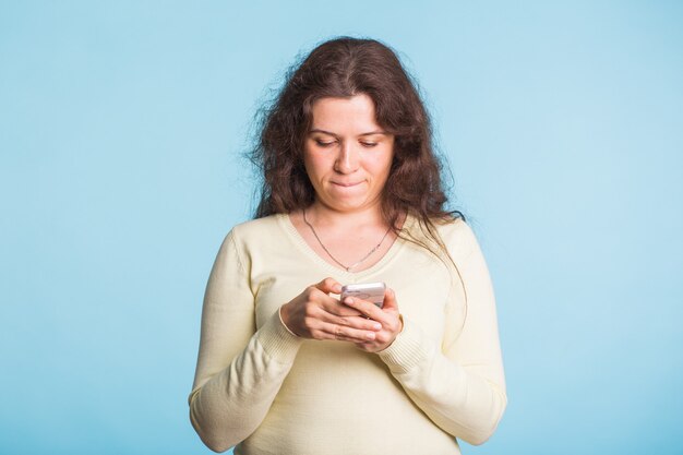 Young Woman using cellphone on blue