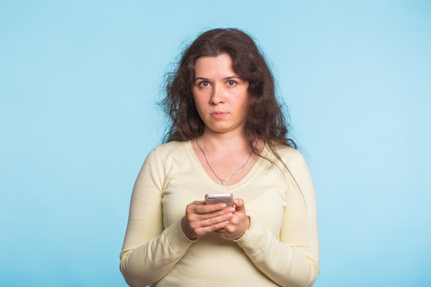 Young Woman using cellphone on blue