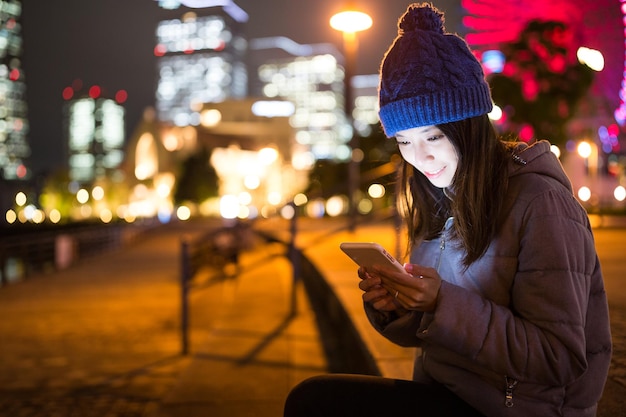 夜に携帯電話を使う若い女性