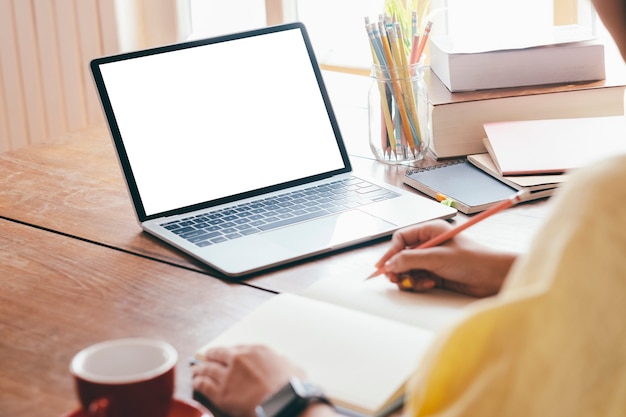 Young woman using computer and writing at home